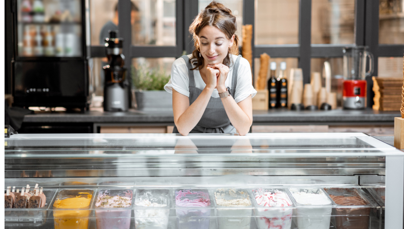 A happy business owner stands at the counter in an ice cream shop