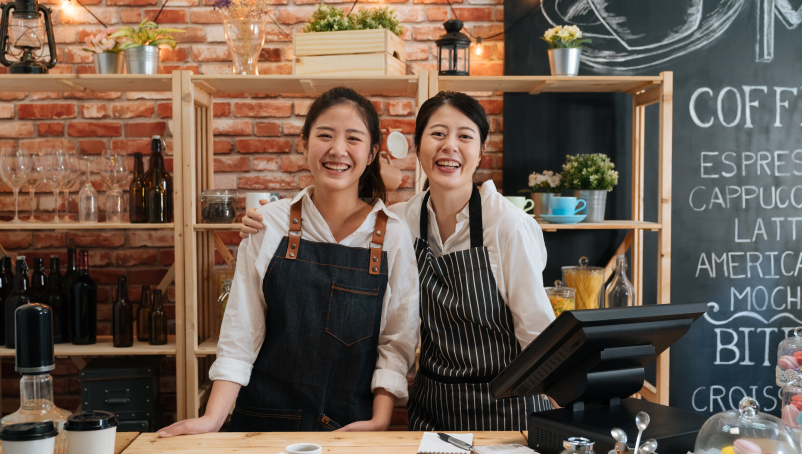 two workers behind the counter in a coffee shop.