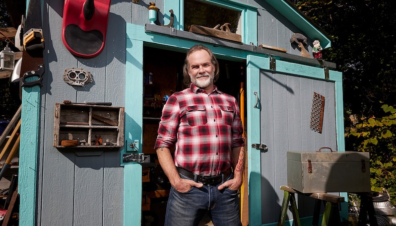 carpenter in front of a woodshed